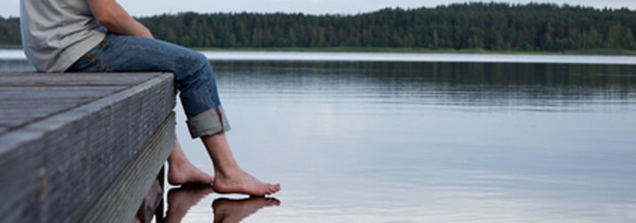 Man sitting on dock with feet touching water